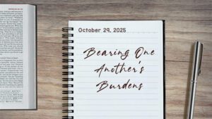 a notebook on a table next to a pen. Journal entry dated October 29, 2025. Entry titled "Bearing One Another’s Burdens"