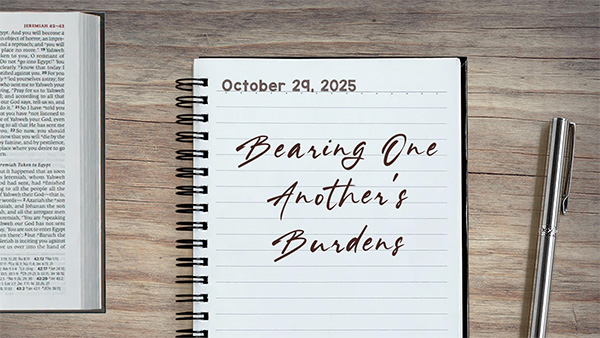 a notebook on a table next to a pen. Journal entry dated October 29, 2025. Entry titled "Bearing One Another’s Burdens"